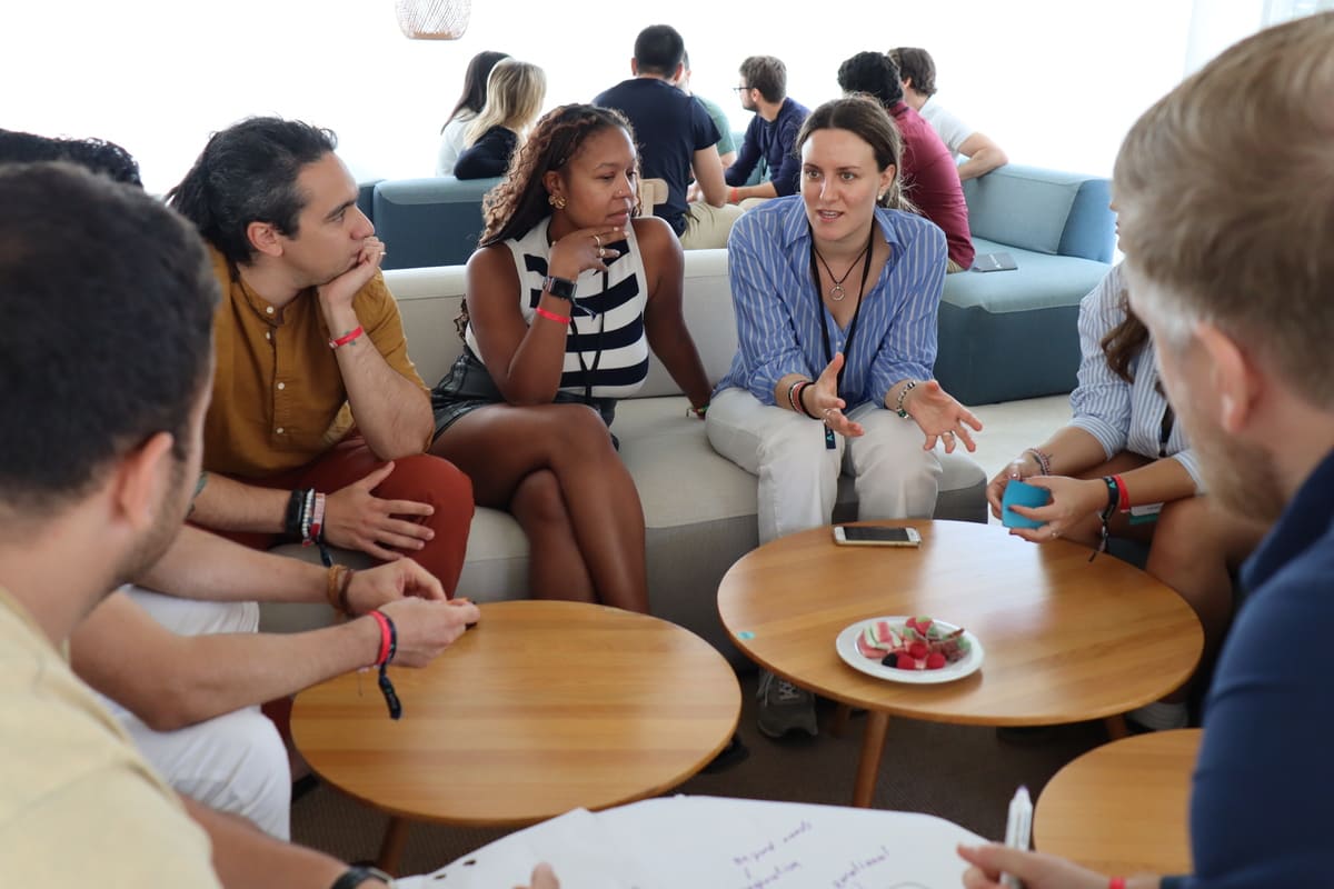 Novas talking in small groups around low tables at a Nova community event