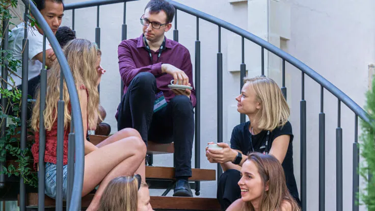 Nova members talking on a staircase at a community meet-up